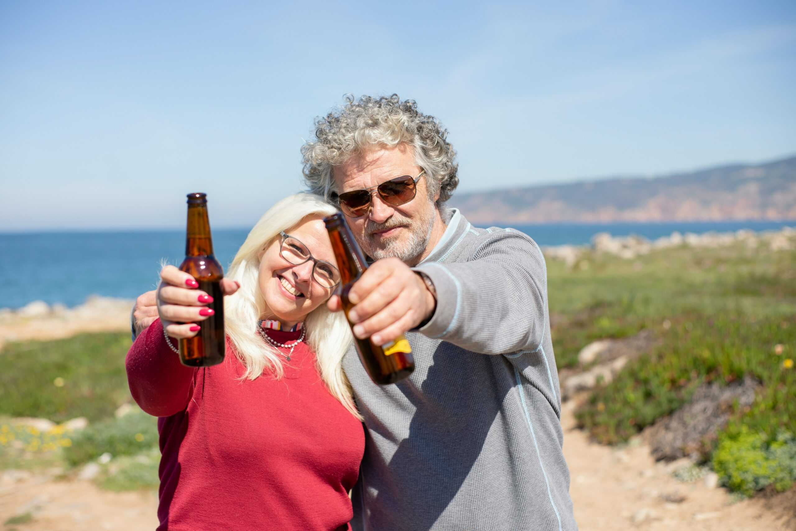 senior man and woman holding beers outside