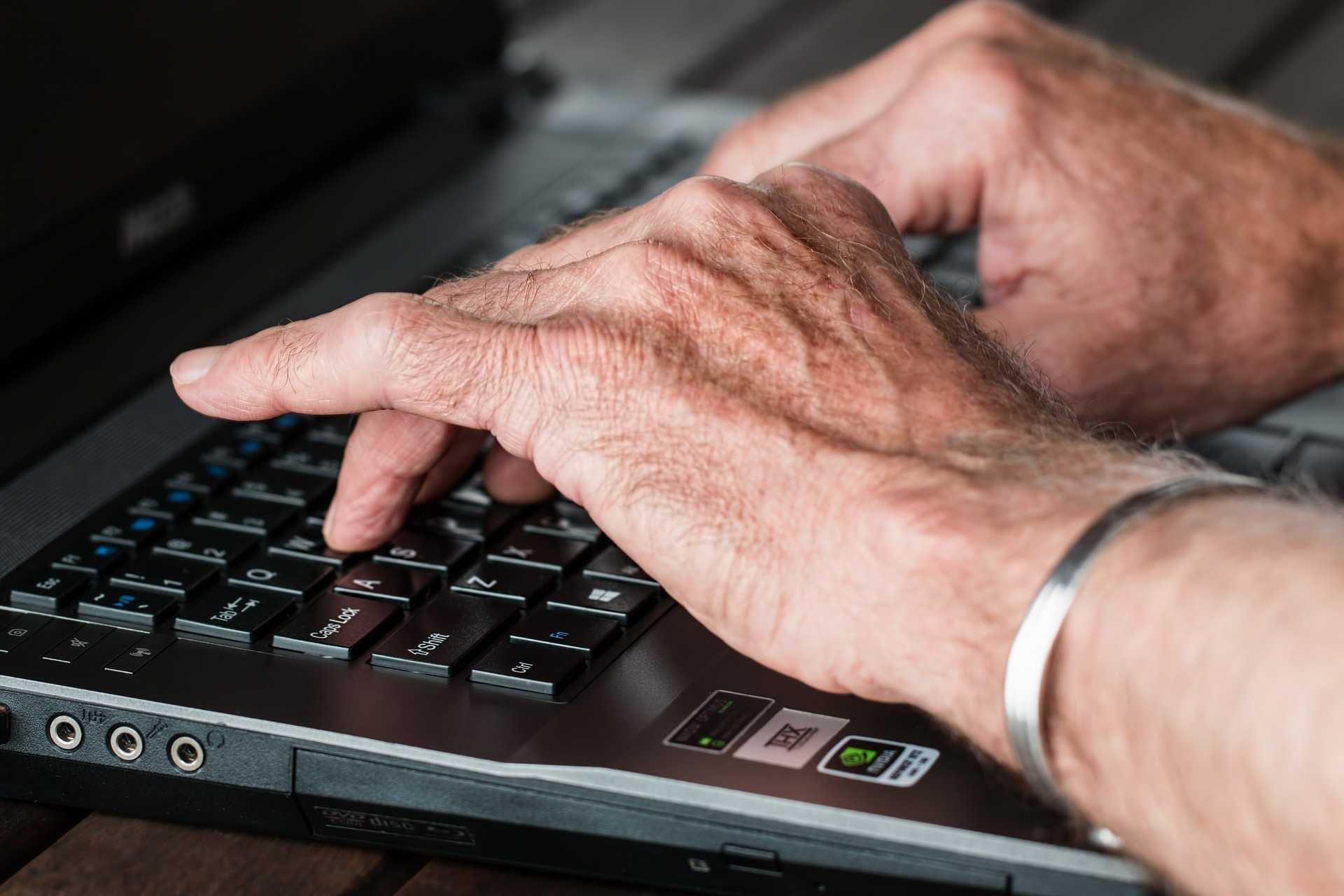 senior hands typing on a computer